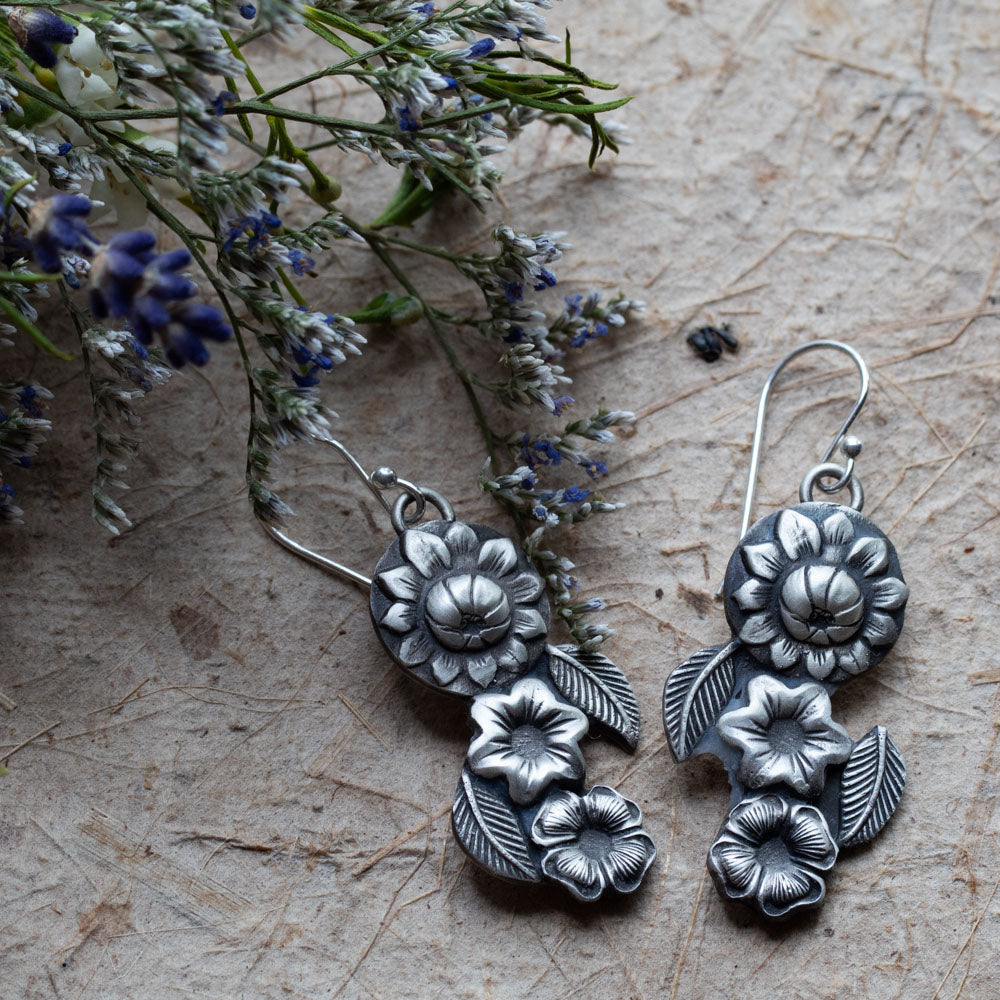 Handmade silver floral dangle earrings featuring layered botanical flower and leaf designs, artisan-crafted with oxidized sterling silver for a vintage nature-inspired look