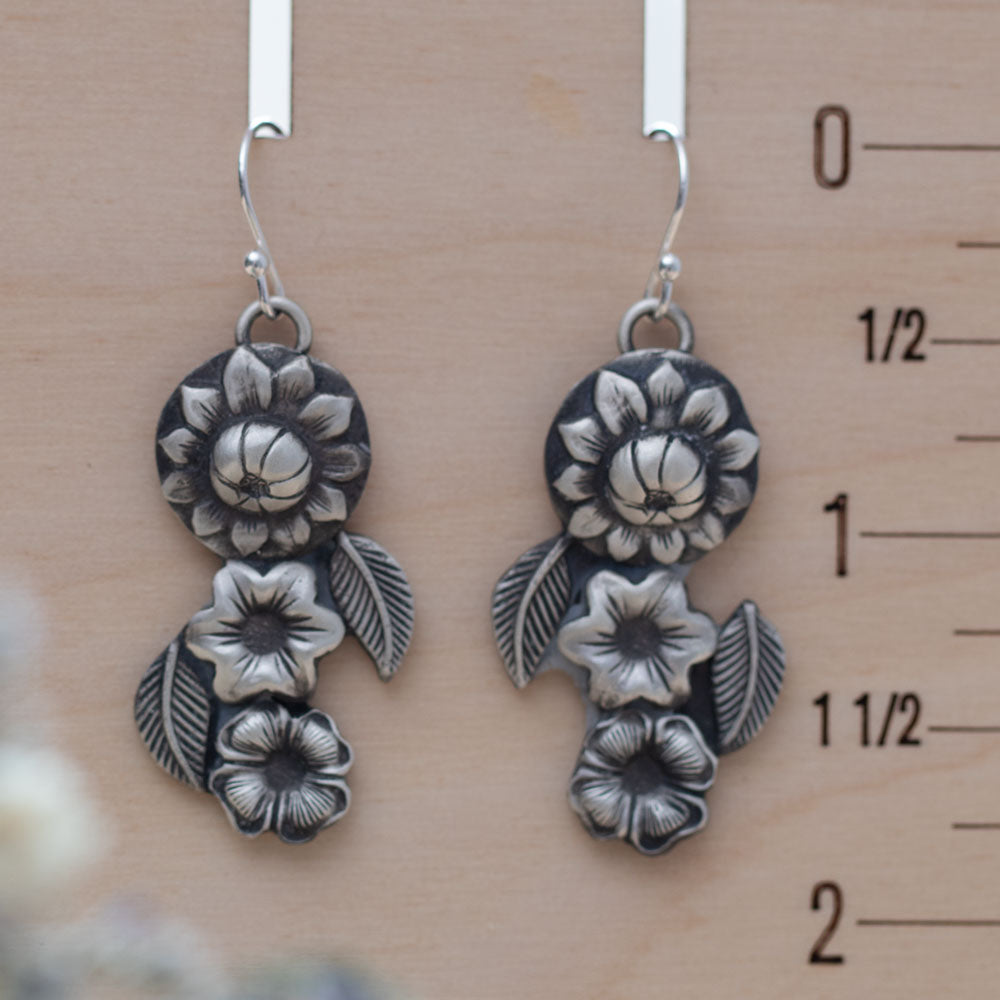 Handmade silver floral dangle earrings featuring layered botanical flower and leaf designs, artisan-crafted with oxidized sterling silver for a vintage nature-inspired look