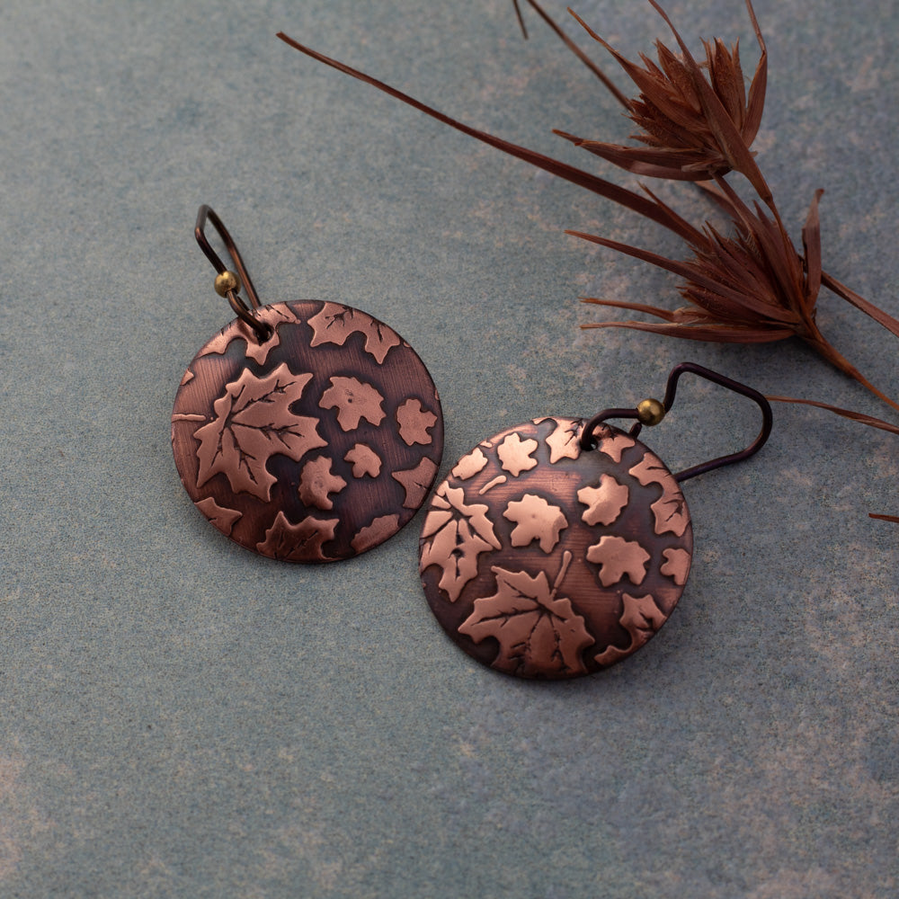 Copper maple leaf earrings with impressed leaf texture, oxidized patina, polished highlights, and niobium ear wires, 1 3/8 inches long, handmade by Divella Designs in Vermont.