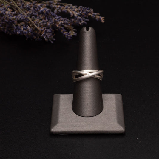 Sterling silver fidget ring displayed on a gray ring stand with lavender sprigs in the background.
