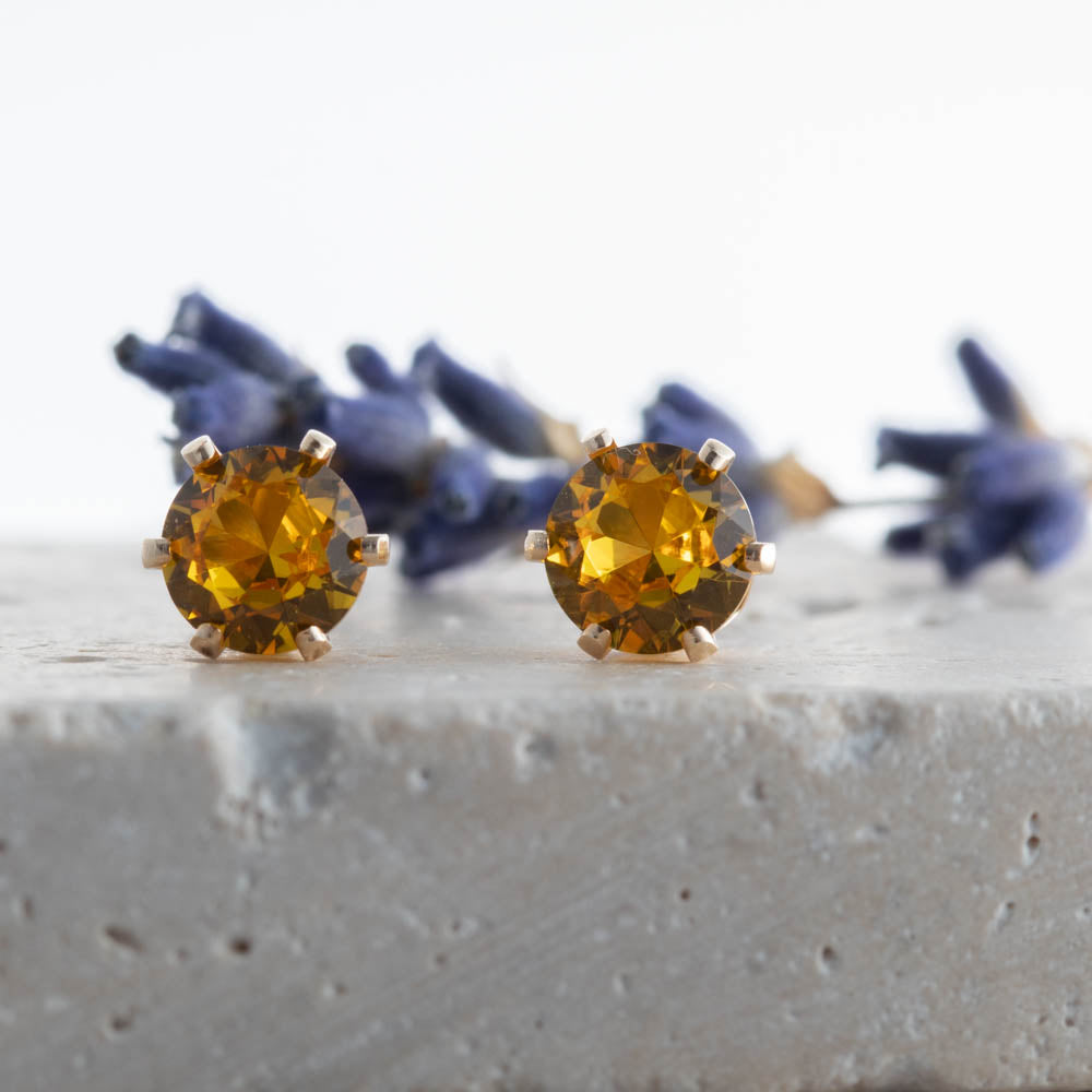 Gold-filled stud earrings with lab golden topaz on stone surface with lavender, handmade in Vermont.