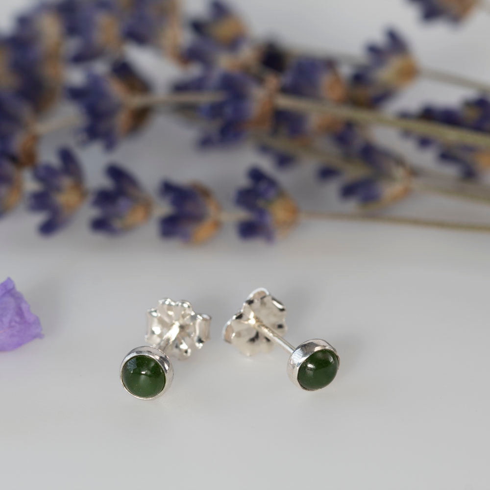 Sterling silver stud earrings featuring round jade gemstones, styled with soft lavender in the background for a natural, elegant look.