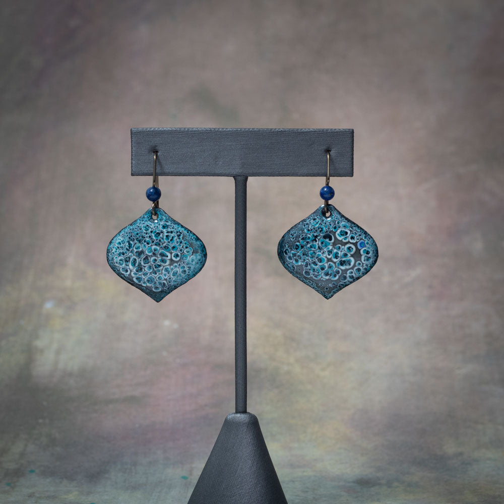 Dark teal and black enamel earrings with textured bubbling detail, handcrafted on copper with niobium ear wires and deep blue accent beads.
