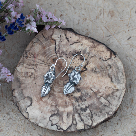 Sterling silver flower and leaf drop earrings by Divella Designs, 1 1/2" dangle with patina finish, handmade in Vermont and photographed on wood with dried flowers