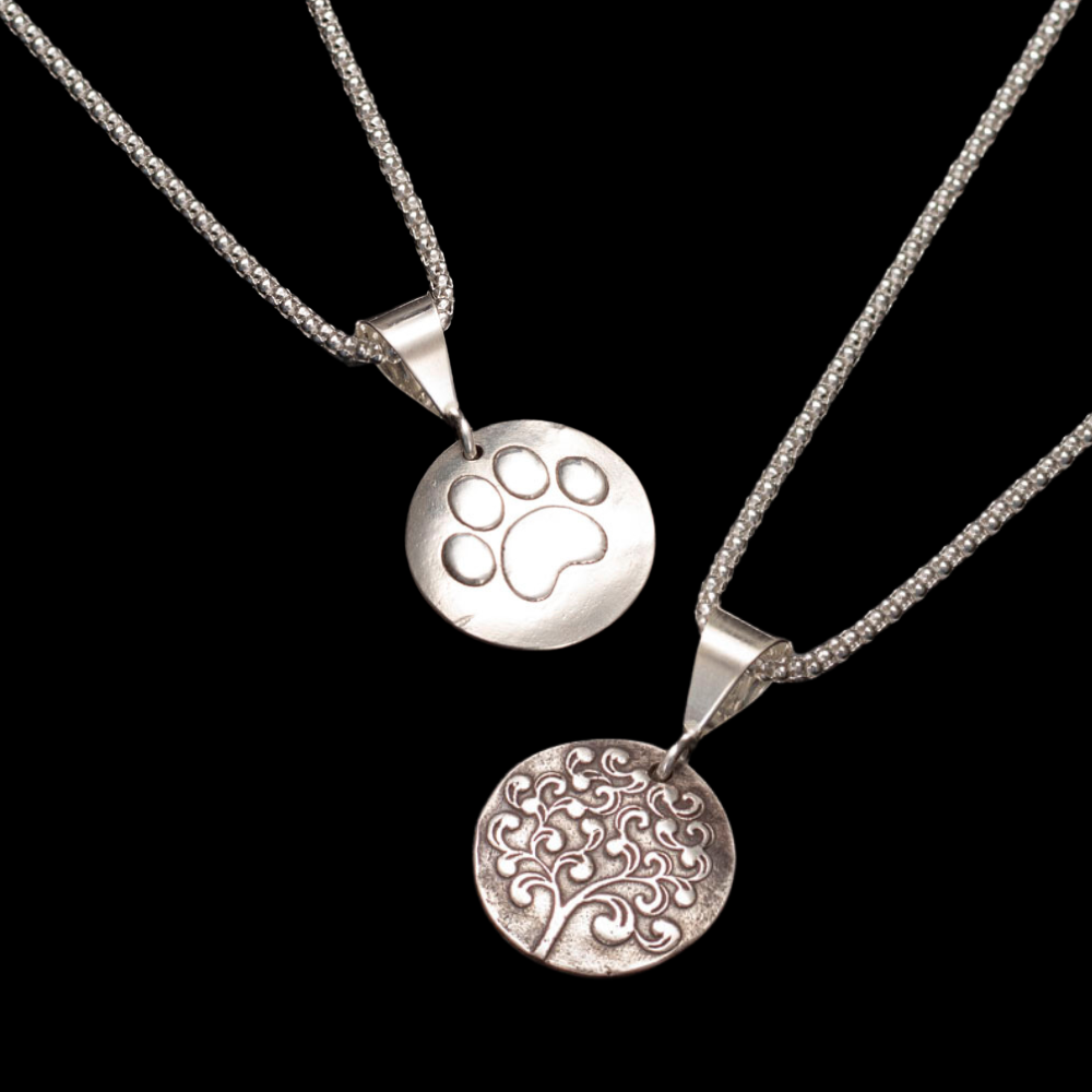 Sterling silver reversible pendant necklace with paw print and tree of life designs on 18-inch chain.