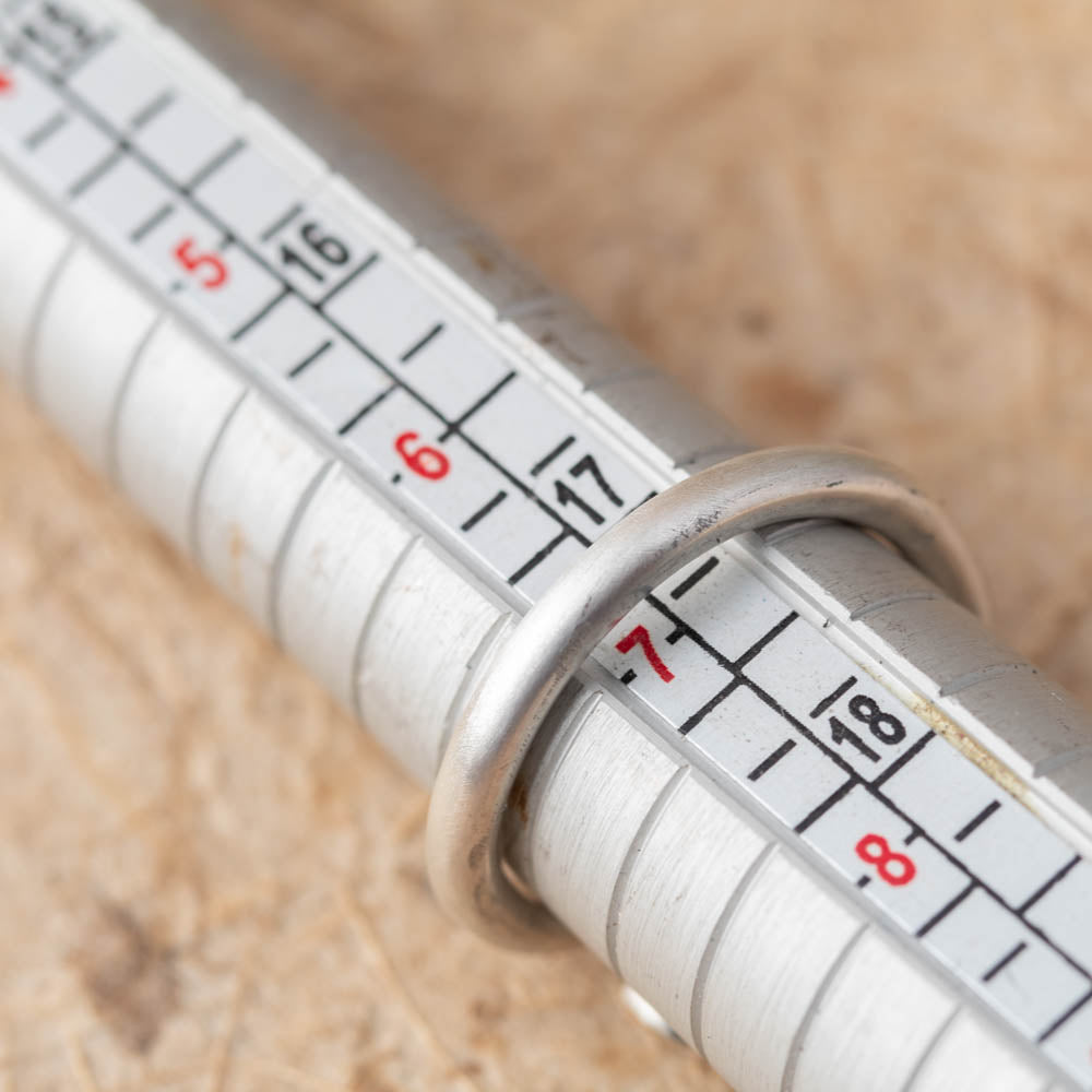Close-up of a ring and a metal ring mandrel on a wooden surface