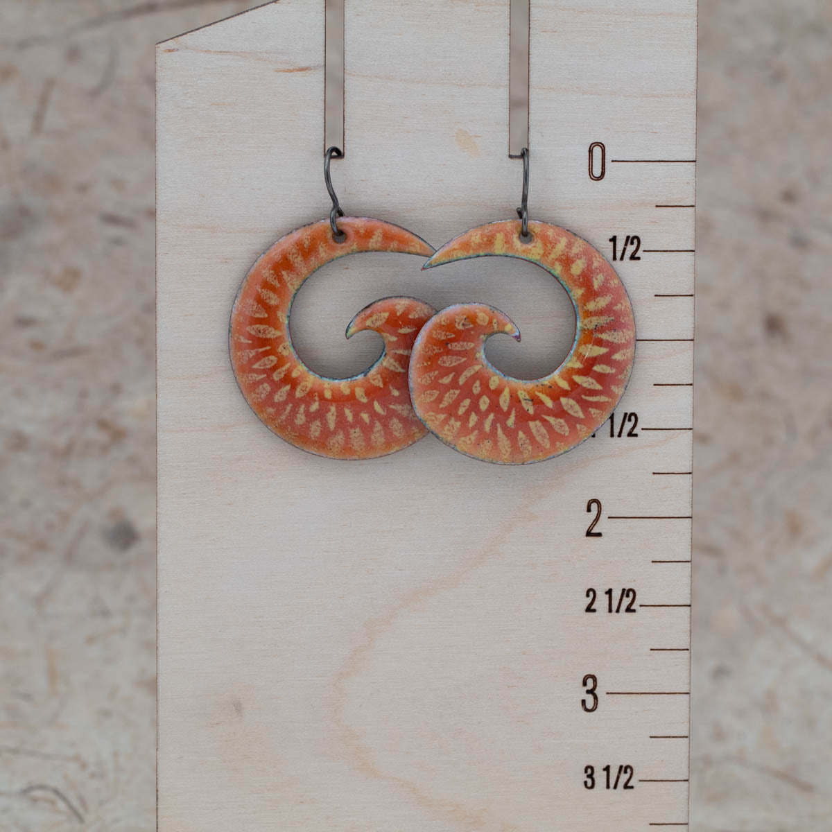 Orange and yellow enamel spiral earrings shown for scale with niobium ear wires.