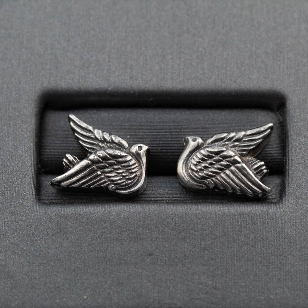 Pair of silver bird-shaped earrings on a gray background