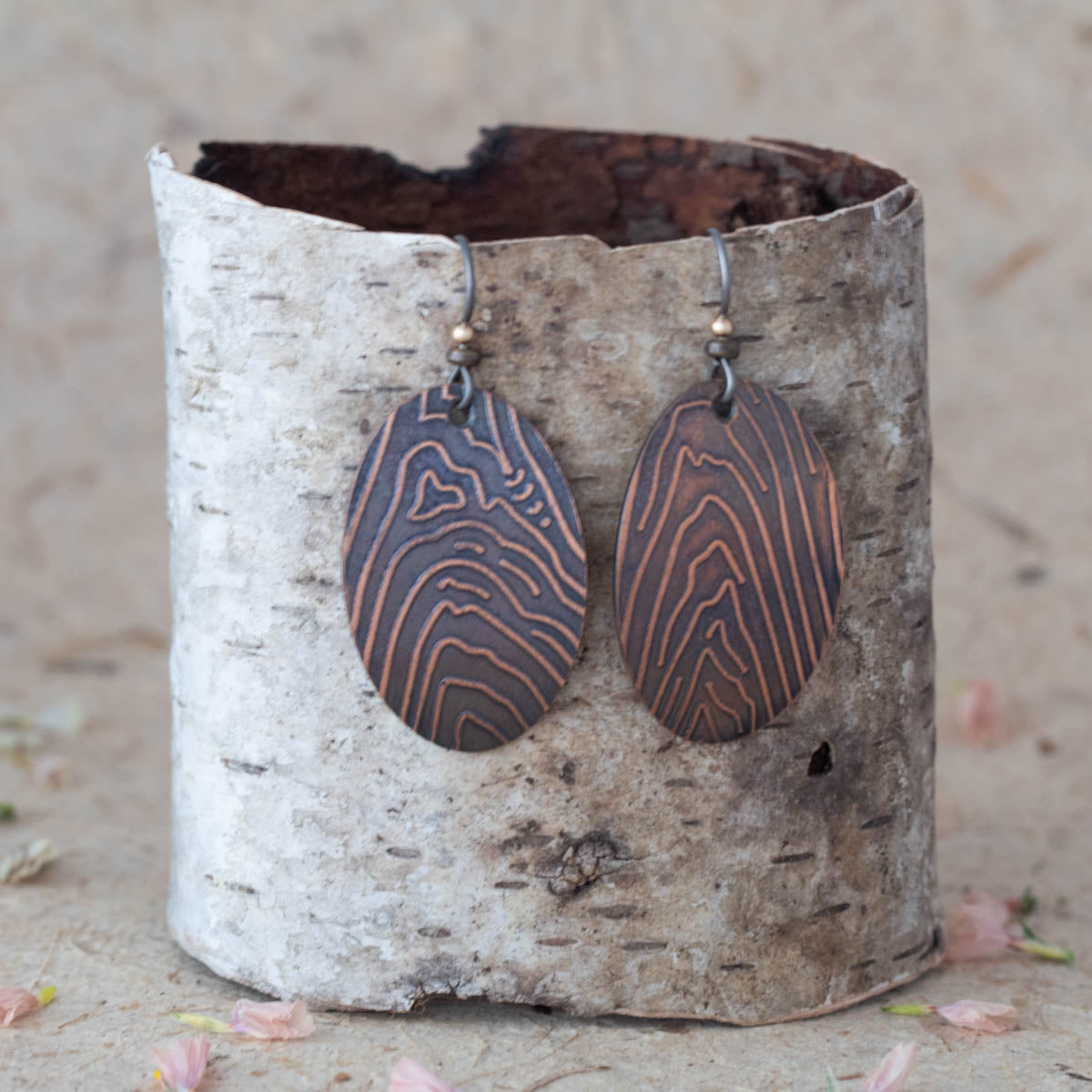 Handmade copper oval dangle earrings with etched woodgrain texture, featuring an earthy rustic finish and nature-inspired artisan design.
