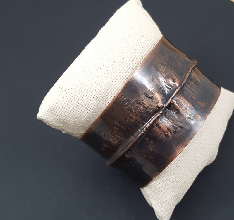 Hand-forged fold-formed copper cuff bracelet with rustic patina, artisan jewelry by Divella Designs, photographed on dark gray background.