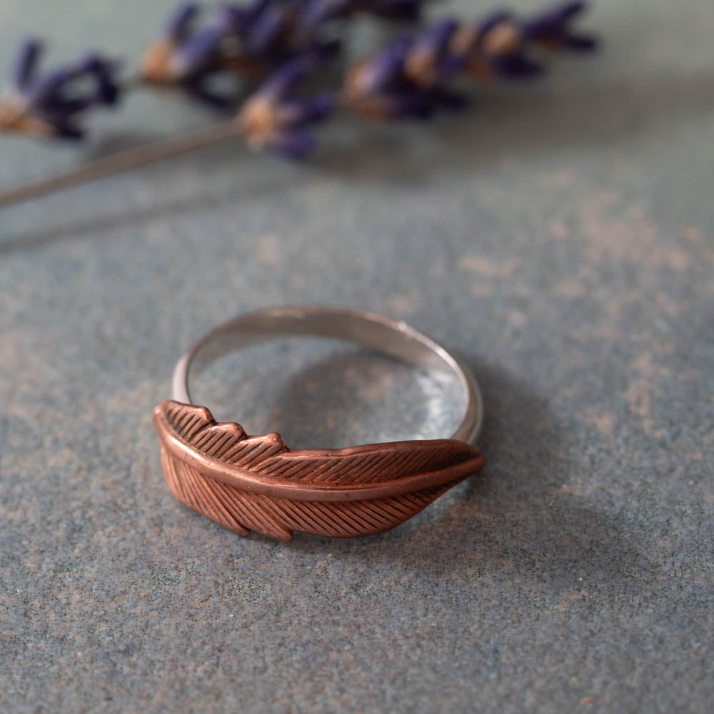Handmade copper feather ring in natural light with soft minimalist styling