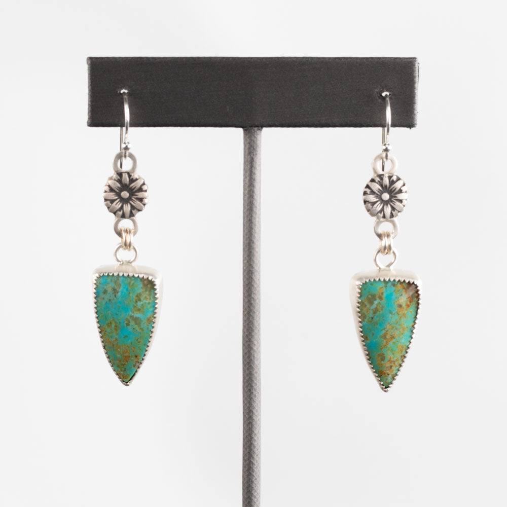 Sterling silver dangle earrings with shield-shaped turquoise stones and stamped floral accents, handcrafted Southwestern-style jewelry by Divella Designs – displayed on white background.