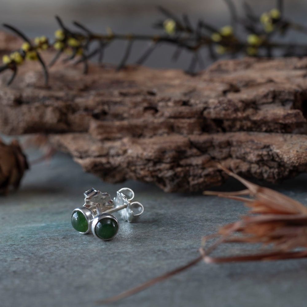 Sterling silver stud earrings featuring round jade gemstones, styled with soft lavender in the background for a natural, elegant loo