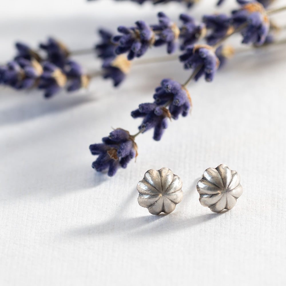 Fluted solid silver stud earrings styled with dried lavender sprigs on a white background.
