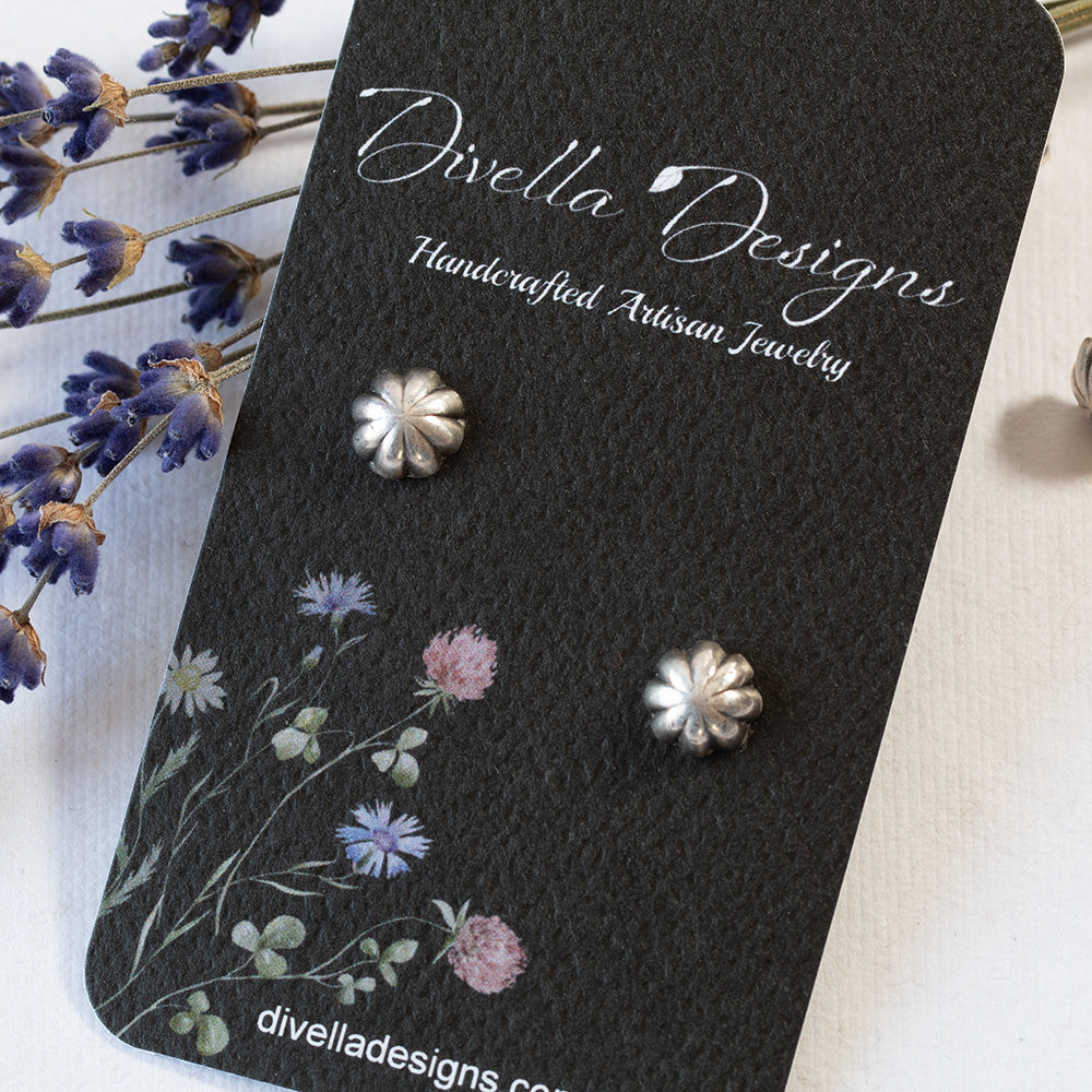 Fluted solid silver stud earrings styled with dried lavender sprigs on a black branded card on a white background.