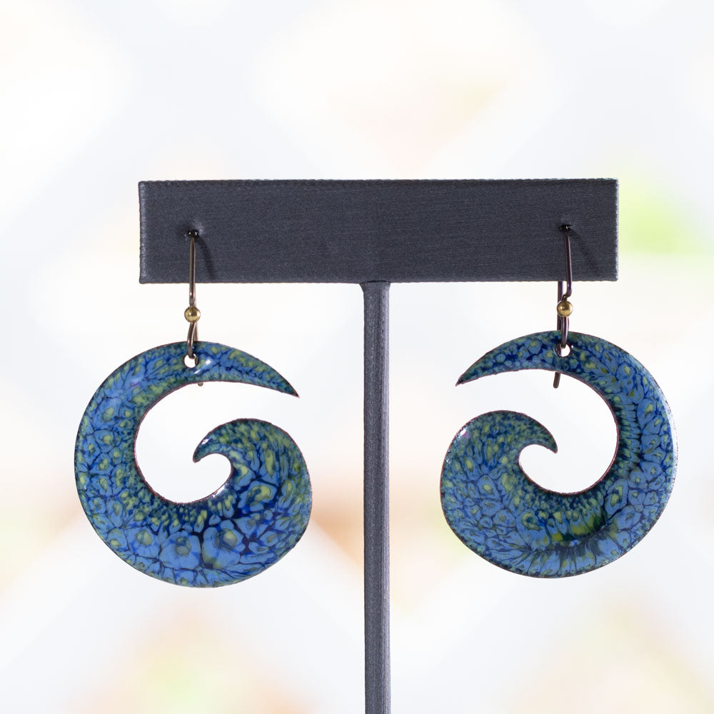 Handmade spiral enamel earrings in vivid blue, yellow, and green with lichen-inspired texture and hypoallergenic niobium ear wires, shown on a neutral background
