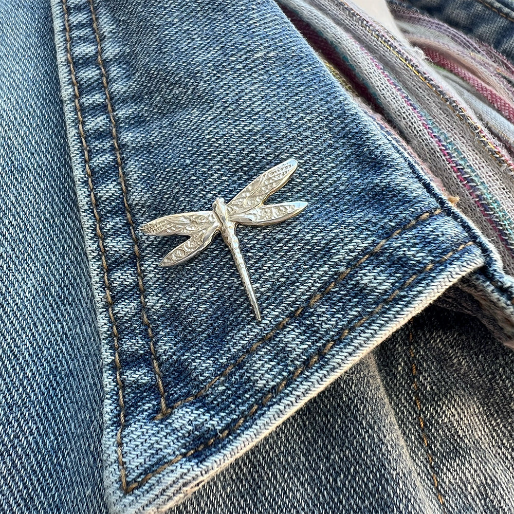 silver dragonfly pin on a denim vest