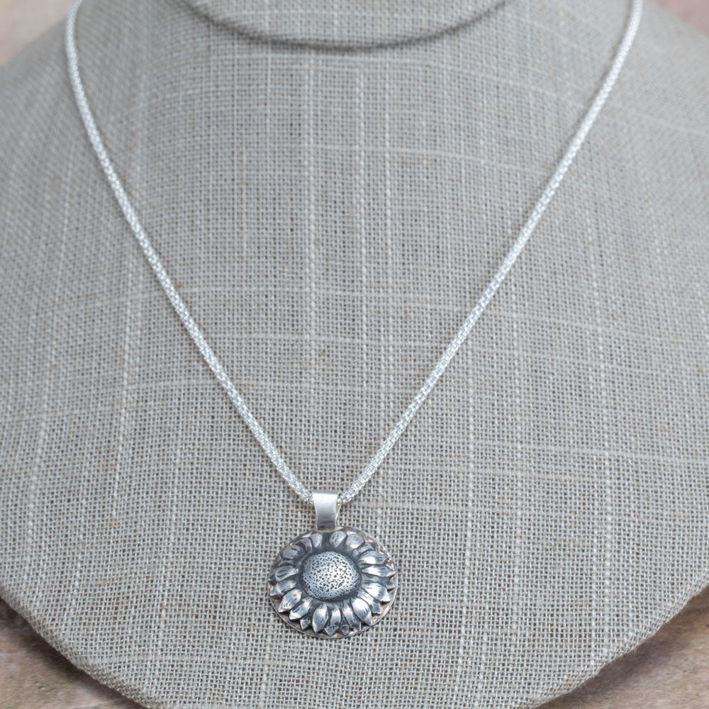 Handcrafted sterling silver sunflower pendant with oxidized details for depth and texture, hanging on a shimmering chain – artisan floral necklace by Divella Designs