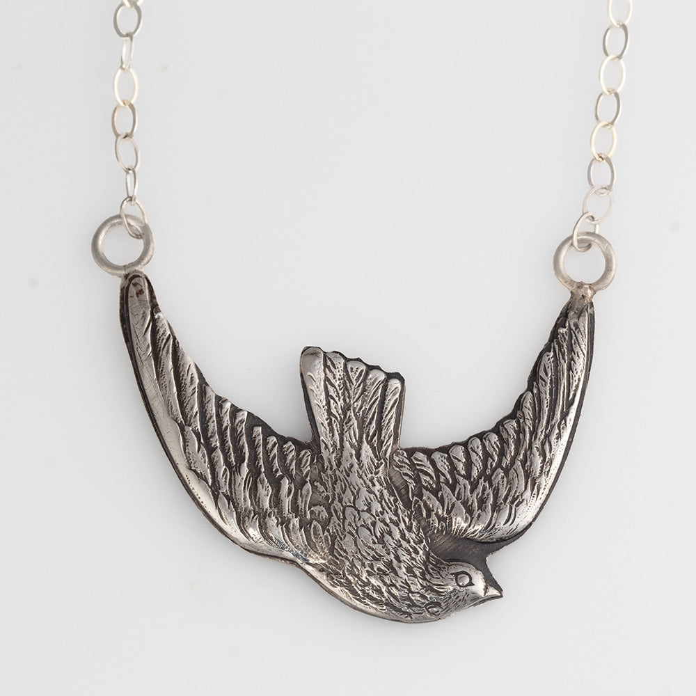 Sterling silver bird in flight pendant necklace with detailed feather texture, displayed on white background.