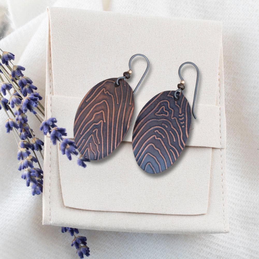 Handmade copper oval dangle earrings with etched woodgrain texture, featuring an earthy rustic finish and nature-inspired artisan design.