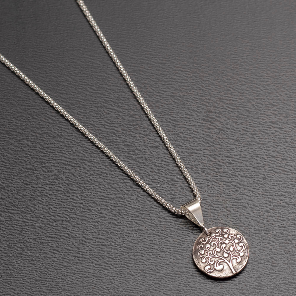 Sterling silver reversible pendant necklace with paw print and tree of life designs on 18-inch chain.