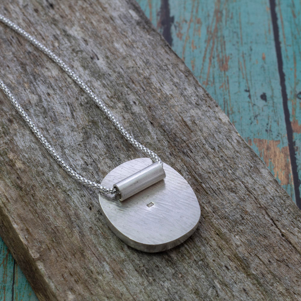Back view of the Boreal Bloom Pendant on weathered wood.