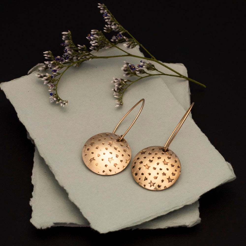 Brass star earrings with impressed celestial texture, 14k gold-filled ear wires, and 1 1/4 inch length, handmade by Divella Designs in Vermont.