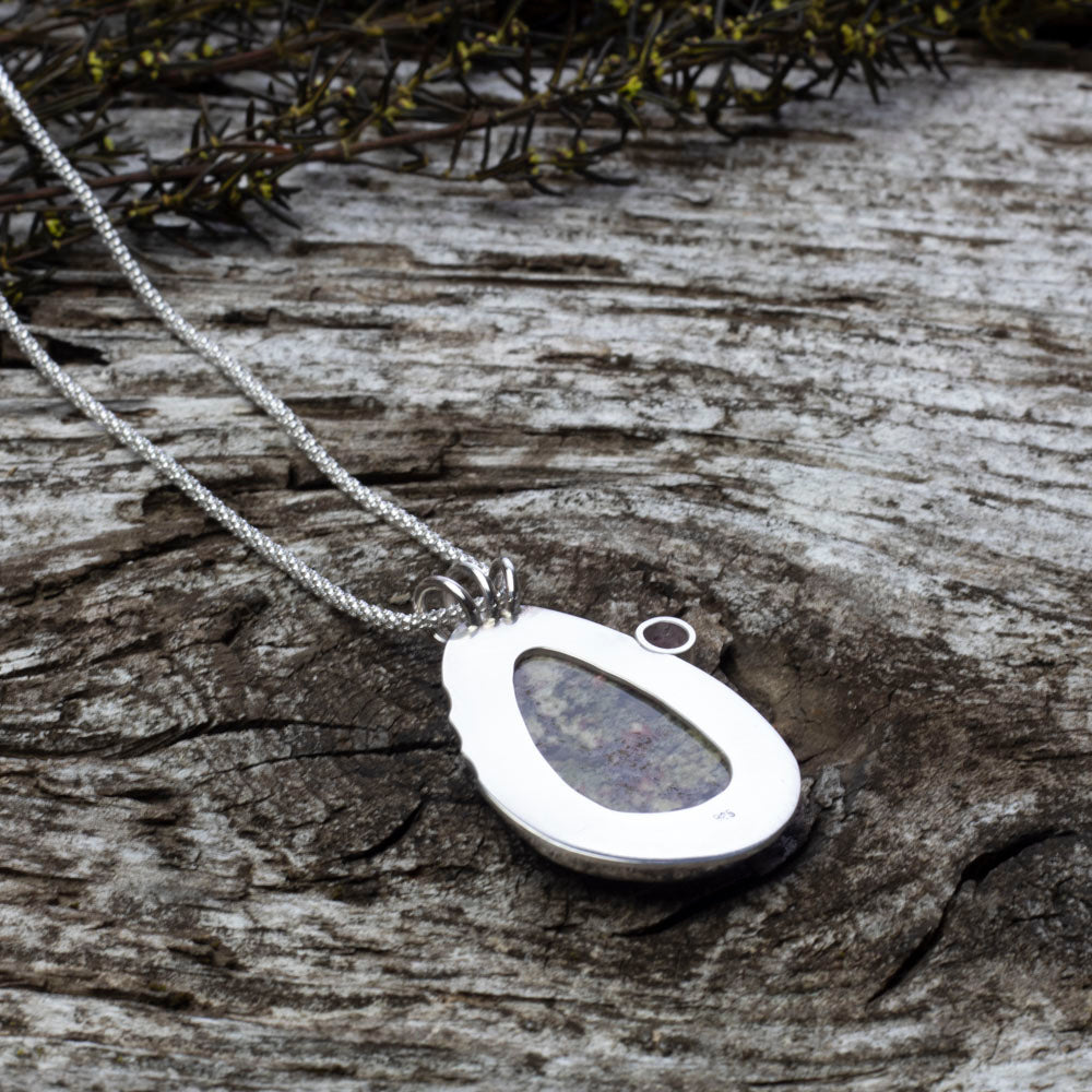 Back of teardrop dendritic agate pendant with pink tourmaline on sterling silver chain.