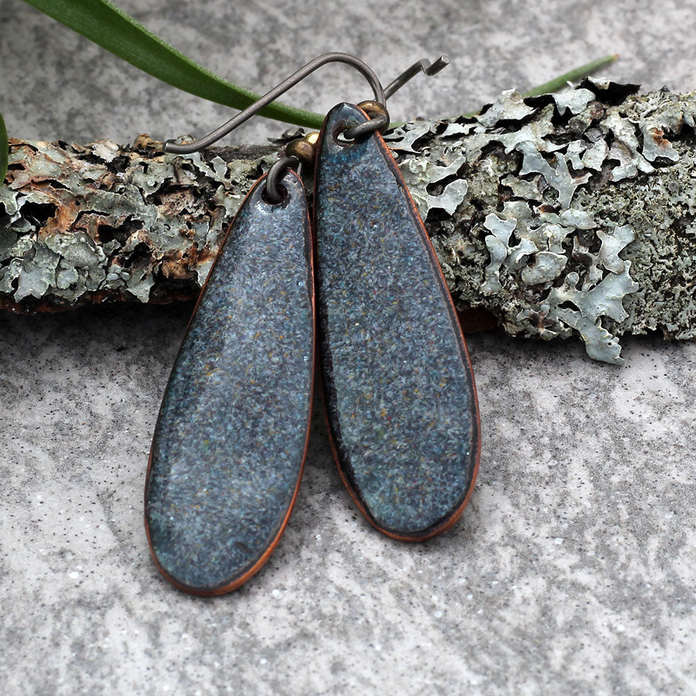 Back view of yellow and green enamel copper earrings showing handmade finish and ear wire attachment.