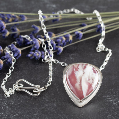 Sterling silver necklace featuring a teardrop-shaped pink and white plume agate stone, bezel set on a textured chain – handcrafted petal-inspired design by Divella Designs