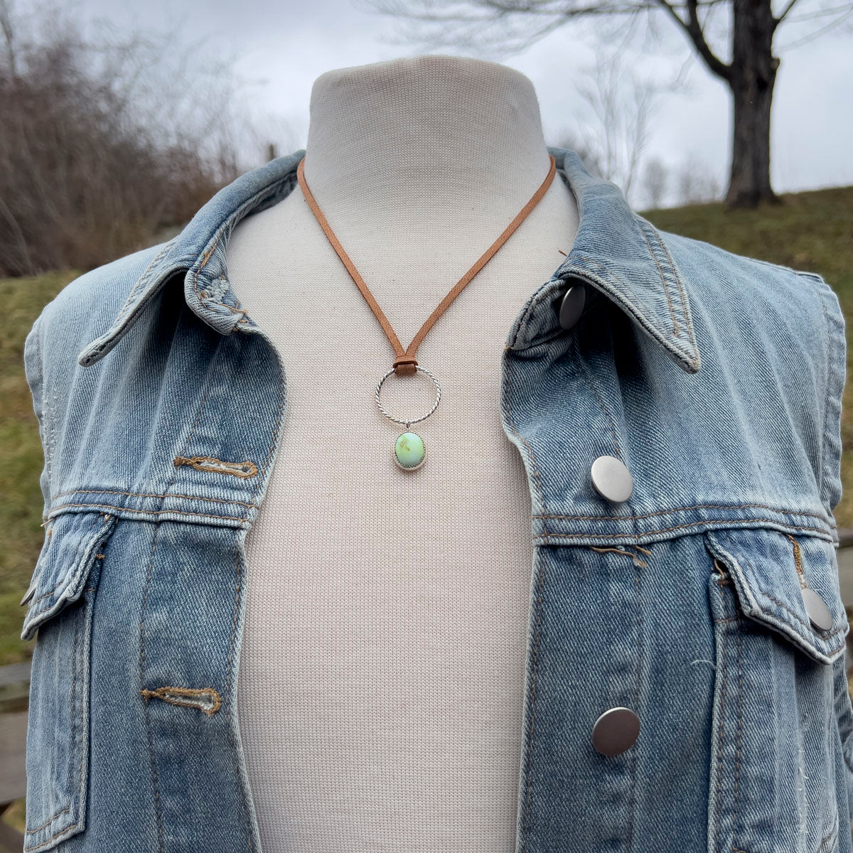 Mannequin wearing a denim jacket with a necklace featuring a variscite pendant.
