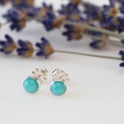 Amazonite and sterling silver stud earrings styled on a white background with lilac sprigs.