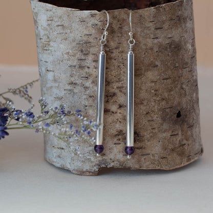 Vertical shot of handmade sterling silver drop earrings with long vertical bars and faceted amethyst gemstones, featuring minimalist modern design and elegant artisan style.