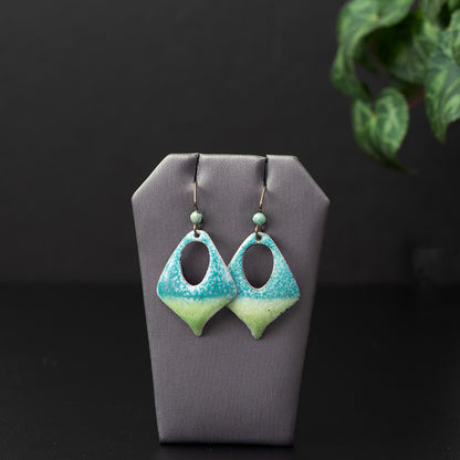 Handcrafted enamel earrings featuring a gradient of aqua blue and lime green with a speckled texture, diamond cutout design, and niobium ear wires accented with light green gemstone beads.