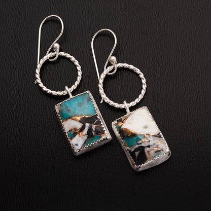 Sterling silver dangle earrings with twisted circle accents and rectangular composite stones made from white buffalo stone, Kingman turquoise, and bronze, displayed on a dark gray background.