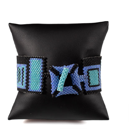 Handwoven beaded cuff bracelet with colorful geometric pattern on black background, fits 7 inch wrist