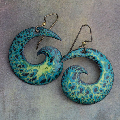 Vibrant spiral enamel earrings in blue, green, and yellow with lichen-inspired texture, handmade with niobium ear wires on a stone background.