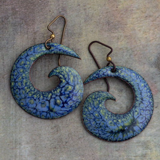 Handmade spiral enamel earrings in vivid blue, yellow, and green with lichen-inspired texture and hypoallergenic niobium ear wires, shown on a neutral background