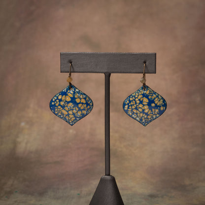 Handmade enamel earrings in deep blue with golden yellow petal pattern and niobium ear wires. Artisan jewelry with a nature-inspired organic texture.