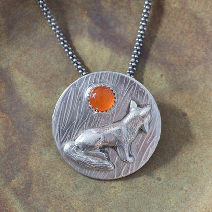 Close-up of sterling silver fox pendant with a 6mm carnelian and textured background