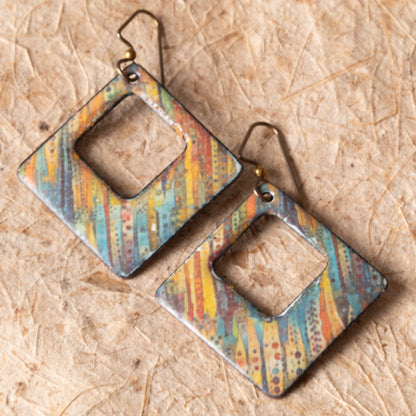 Colorful open square enamel earrings with teal, gold, rust, and orange line details on niobium ear wires.