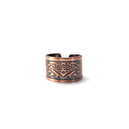 Copper ear cuff with intricate design on a white background