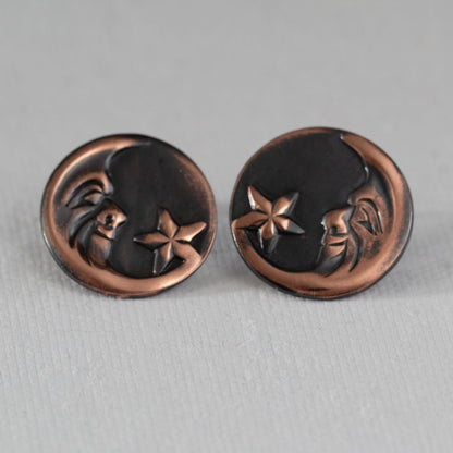 Oxidized copper post earrings featuring a crescent moon and star design – celestial jewelry with embossed face motif on dark patina background, artisan handcrafted style.