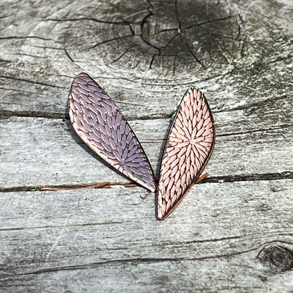 Handcrafted copper post earrings with etched botanical texture – leaf-shaped design, nature-inspired jewelry photographed on rustic weathered wood background.
