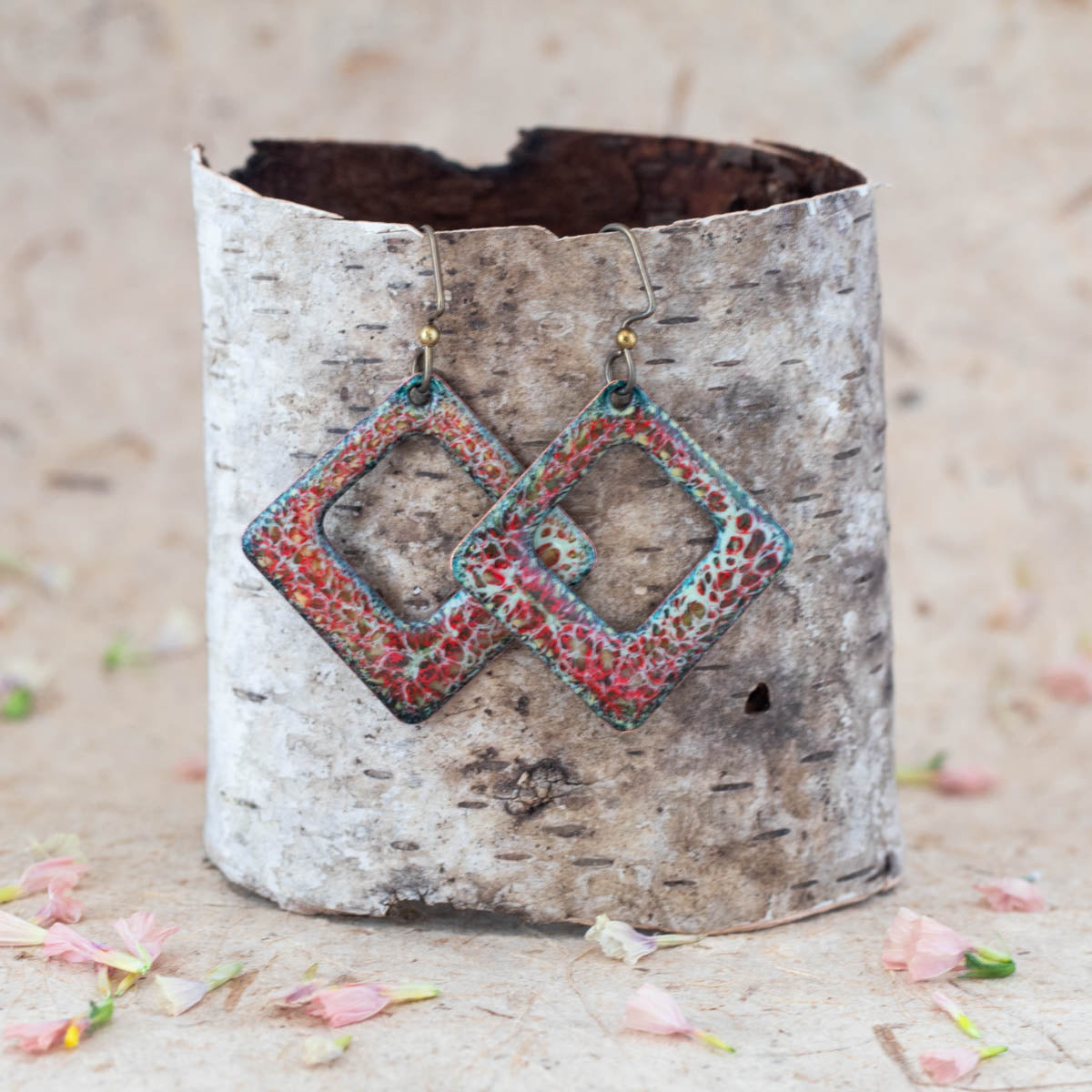 Handmade enamel diamond-shaped dangle earrings in coral red, turquoise, and cream tones, featuring open geometric design with textured organic pattern on copper.