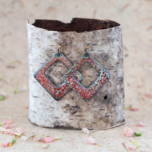 Handmade enamel diamond-shaped dangle earrings in coral red, turquoise, and cream tones, featuring open geometric design with textured organic pattern on copper.