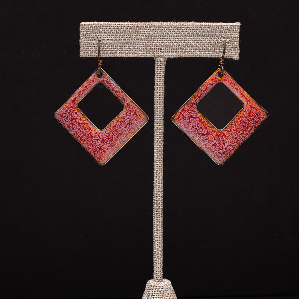 Square-shaped cranberry red enamel earrings with a delicate crackle pattern, displayed on ab earrings stand on a black background.