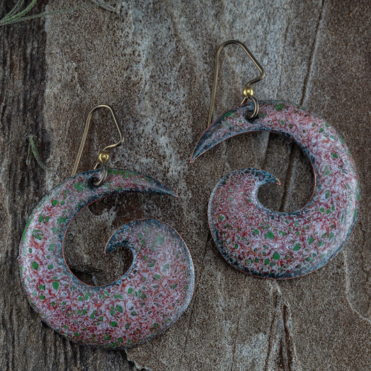 Large spiral enamel earrings in red, white, and green speckled pattern with a high-gloss finish, displayed on a black background with niobium ear wires.