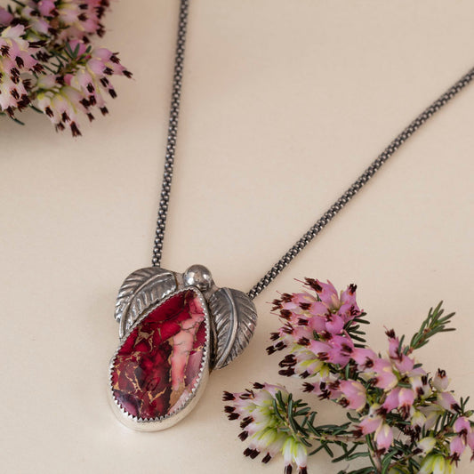 Sterling silver necklace with teardrop dahlia jasper stone in shades of pink and red, accented by two detailed silver leaves and a polished silver bead, handmade botanical jewelry.
