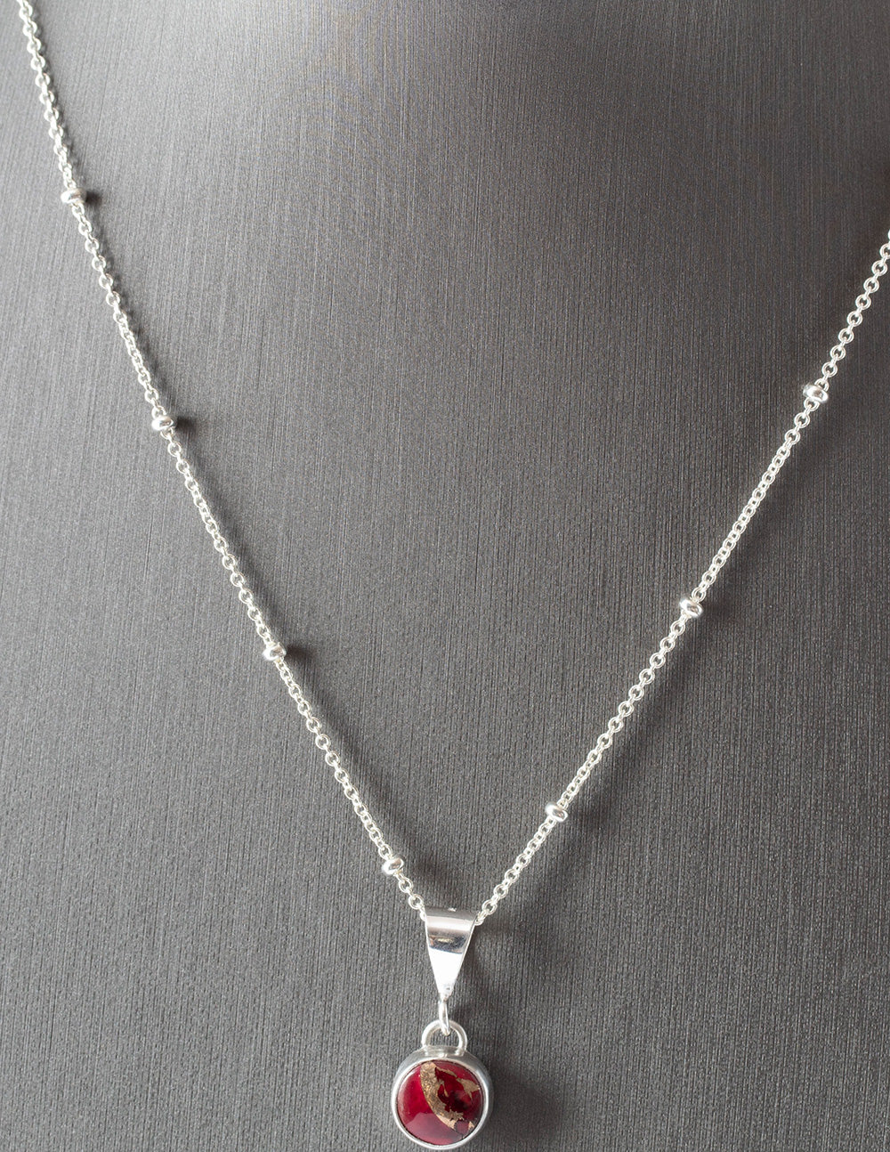 Dainty handmade sterling silver pendant necklace with round red and pink dahlia jasper stone, set on a fine chain with minimalist floral design and artisan elegance.